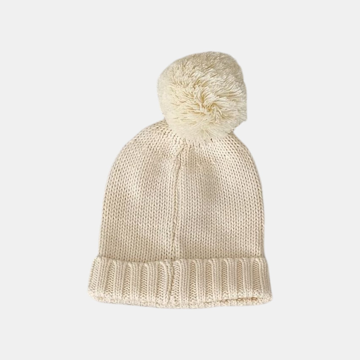 Knitted cream baby beanie with a pom-pom on a light grey background
