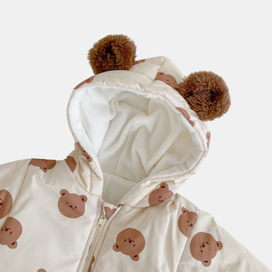 White baby pramsuit with bear patterns and brown pom-pom ears on a white background