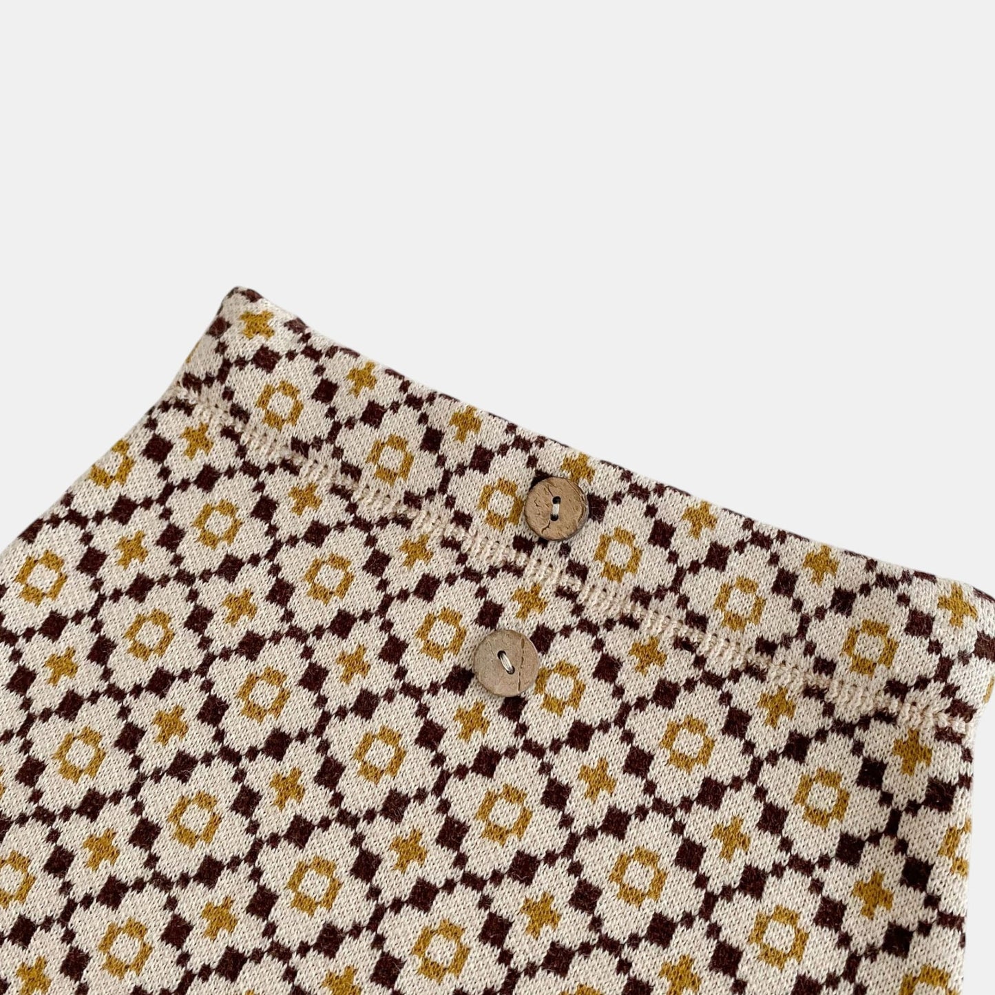 Close up of baby knit bloomers with a floral design on a white background