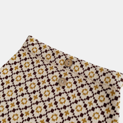Close up of baby knit bloomers with a floral design on a white background