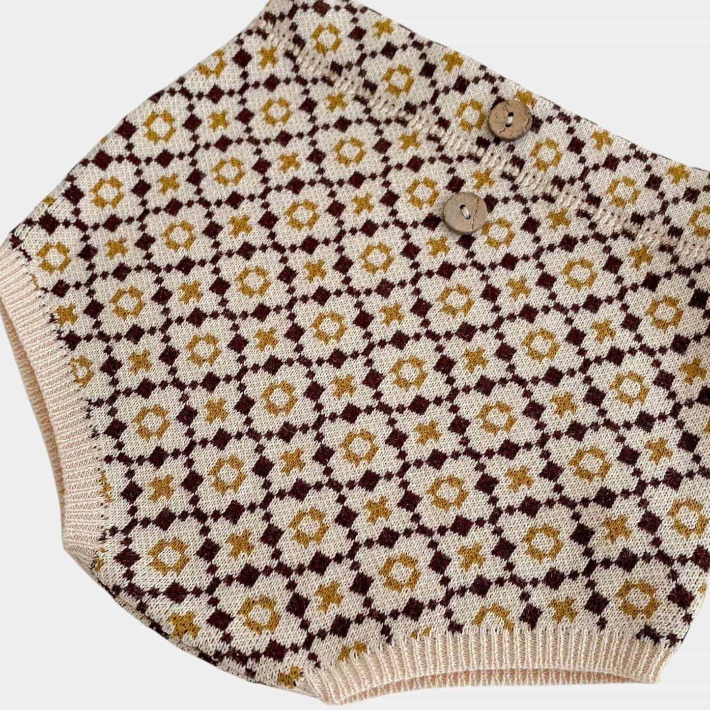 Knitted brown baby bloomers with floral pattern on a white background