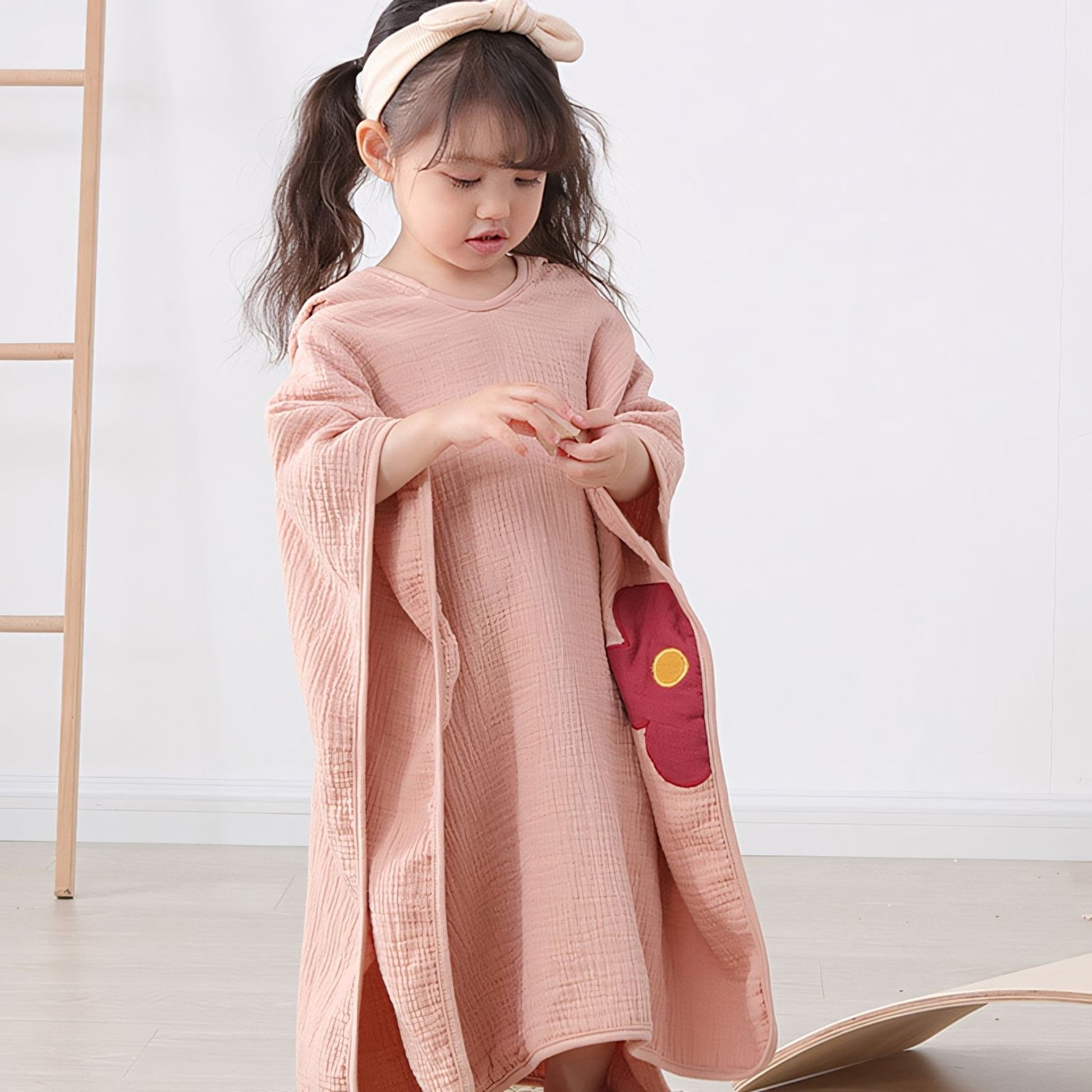 Girl in pigtails wearing Little Flower Cotton Hooded Towel Poncho, Apricot - Bambisserie