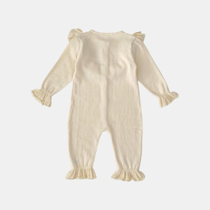 Back of cream baby romper with ruffled sleeves and legs on a white background