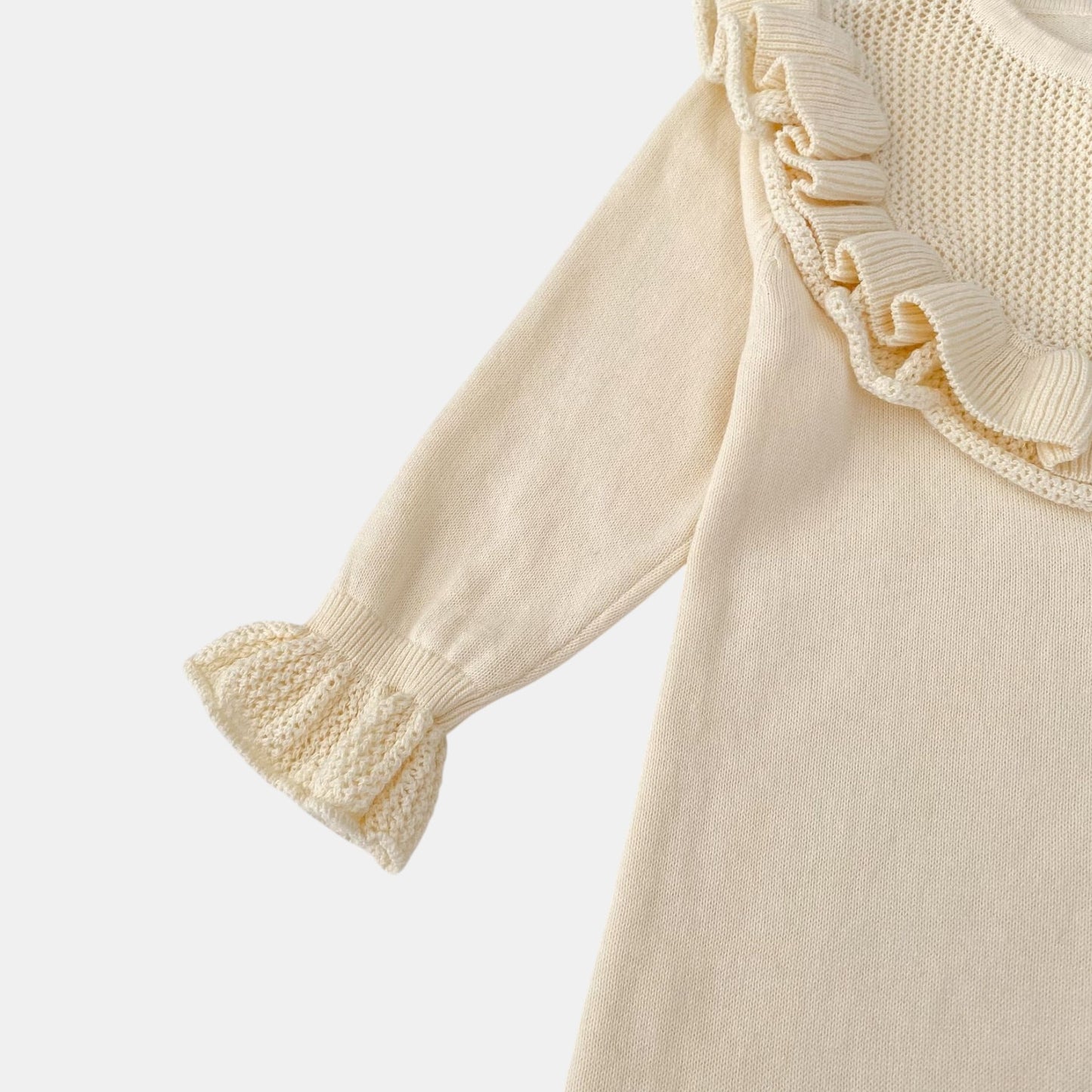 Cream romper with ruffled cuffs on a light grey background