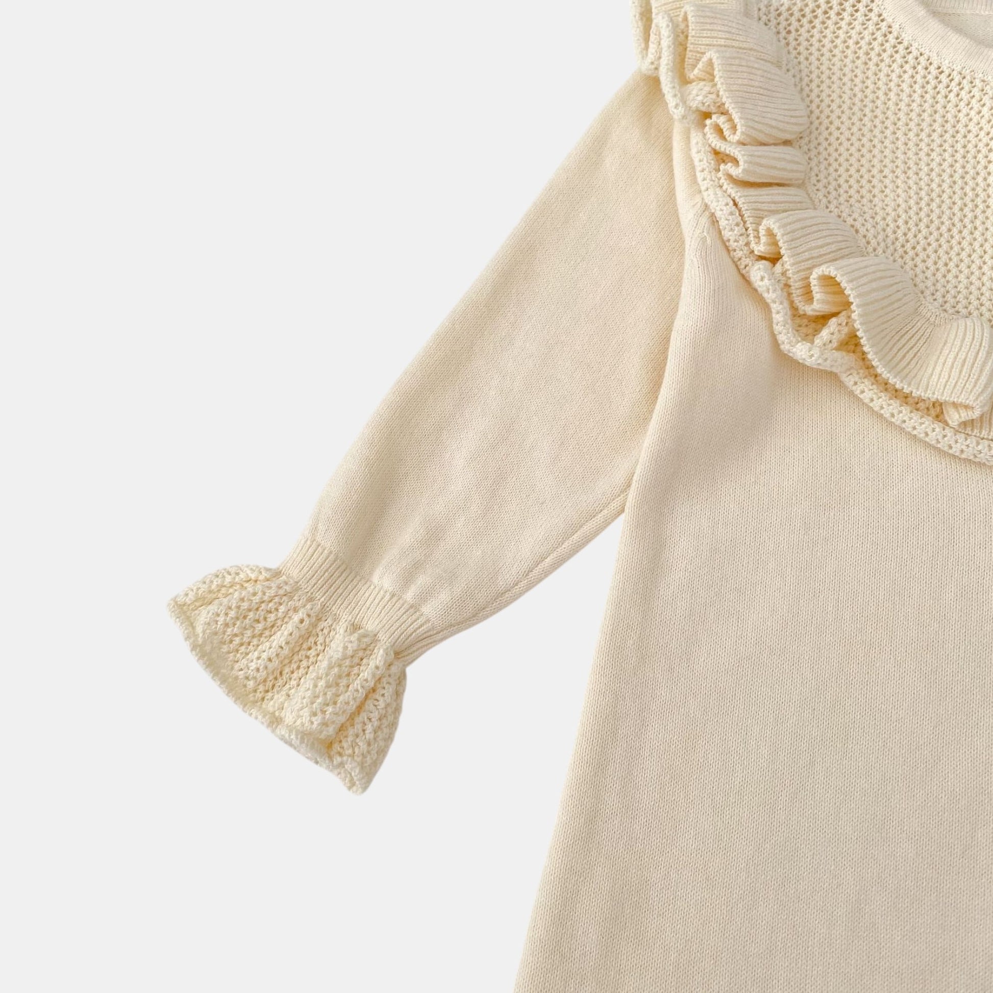 Cream romper with ruffled cuffs on a light grey background