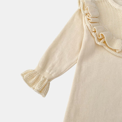 Cream romper with ruffled cuffs on a light grey background