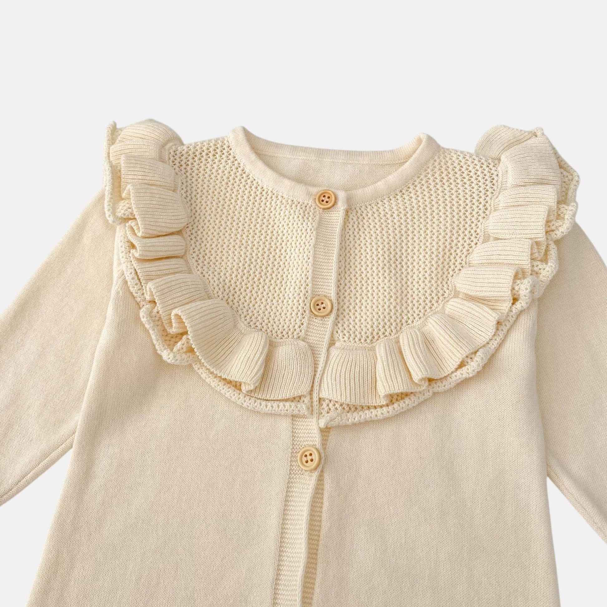 Cream knitted baby romper with ruffled collar on a white background