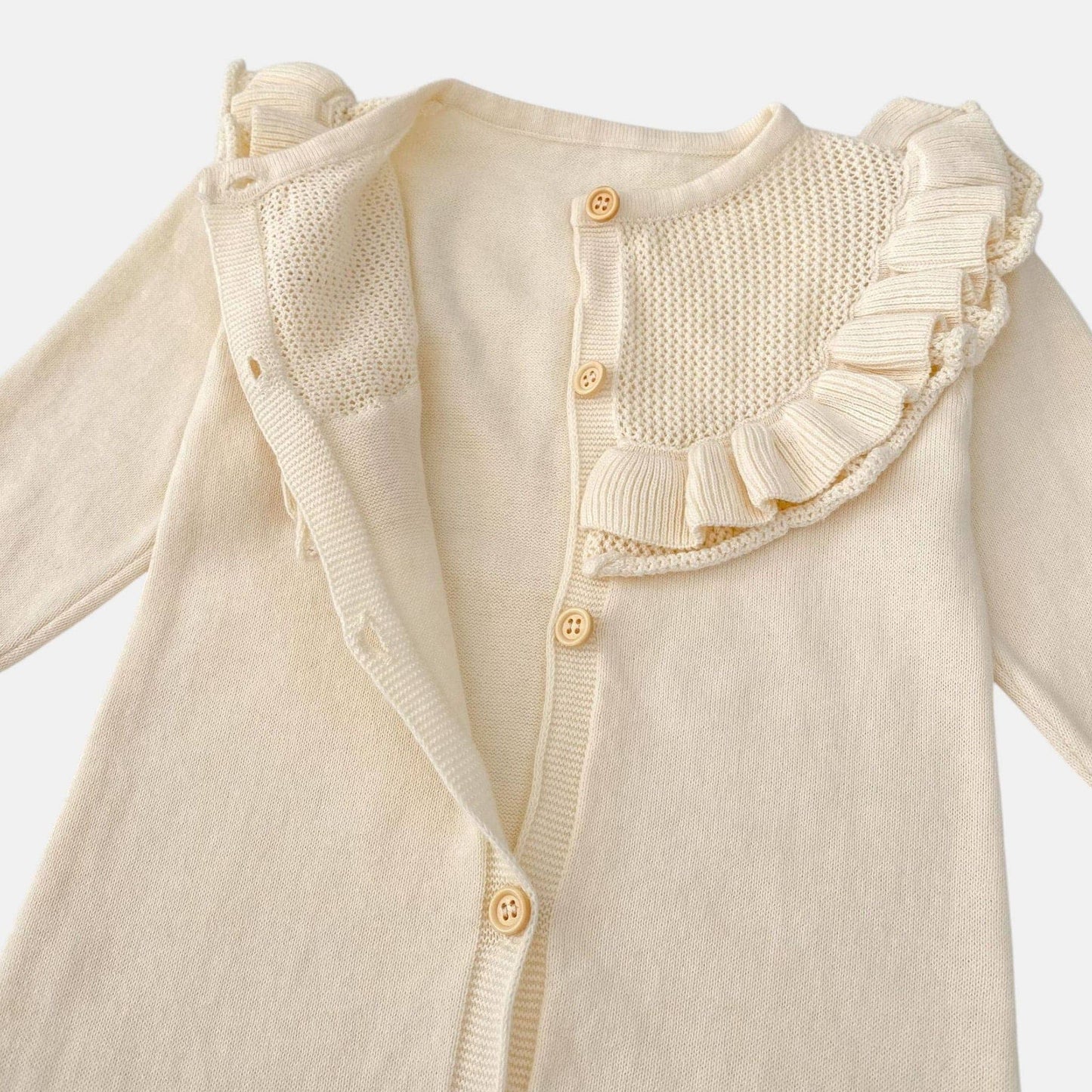 Cream baby romper with ruffled shoulders on a light grey background