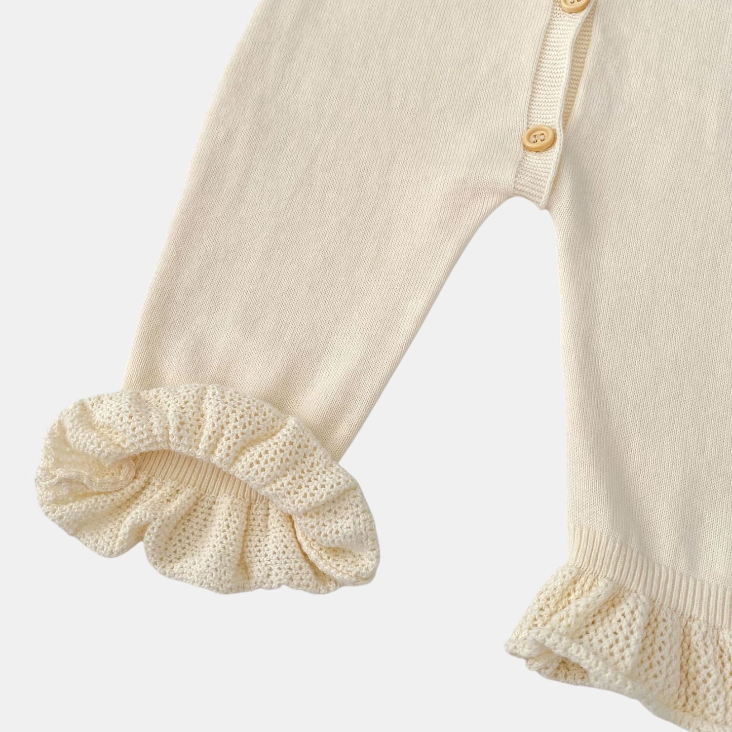 Close-up of a cream baby romper with ruffled details on a light grey background