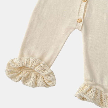 Close-up of a cream baby romper with ruffled details on a light grey background