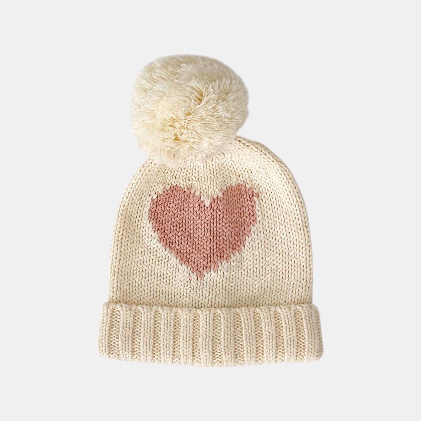 Knitted baby cream beanie with a pink heart design and pom-pom on a white background