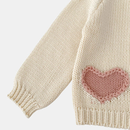 Cream knitted sweater with a pink heart patch on a light grey background