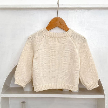 Back of cream knit baby cardigan on a wooden hanger against a white background