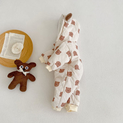 Baby pramsuit with bear pattern and teddy bear toy on a light background